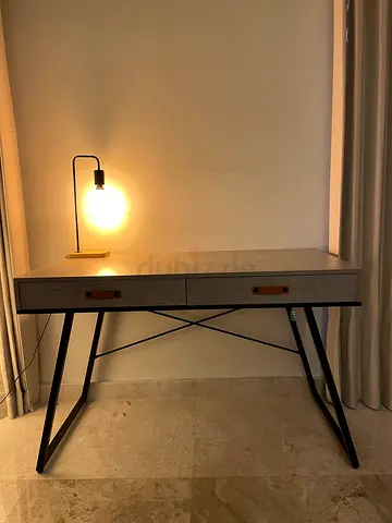 Grey office desk with drawers and metal legs with faux leather handles.