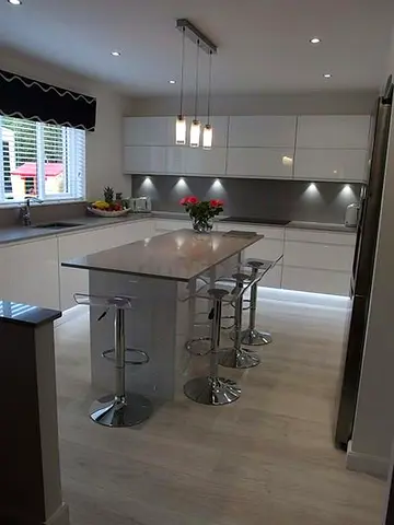Modern white kitchen with island and bar stools - well maintained