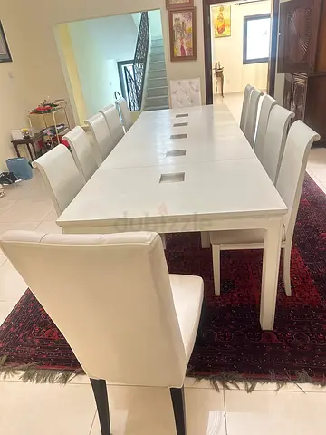 White modern dining table with 12 upholstered wooden chairs