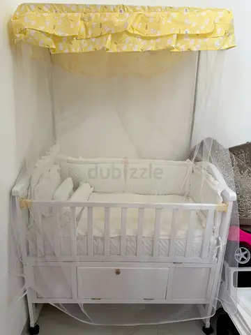 White baby crib with built-in storage and mosquito net