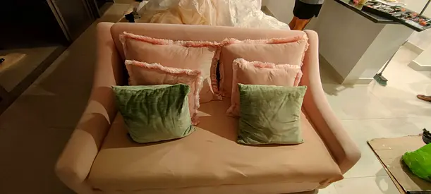Small two-seater pink fabric loveseat with cushions
