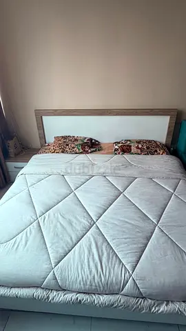 King sized wooden bed frame with upholstered headboard along with a small bed table