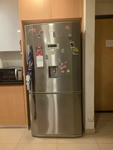 Well-maintained stainless steel fridge with bottom freezer, water dispenser
