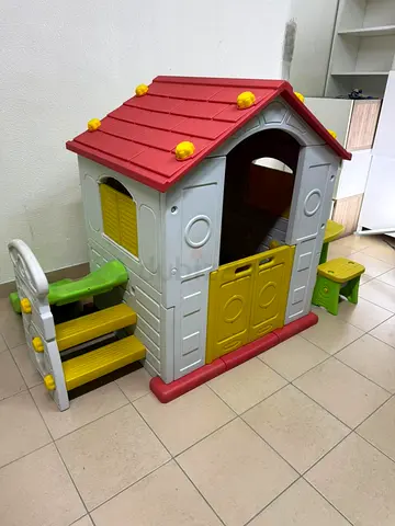 It is a playhouse designed for children, equipped with a table and two chairs.