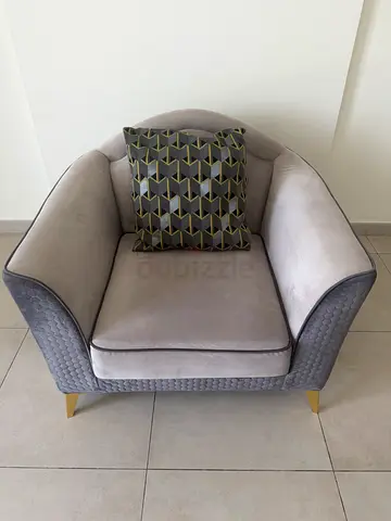 Grey upholstered armchair with gold legs