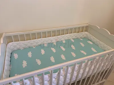 White wooden baby crib with mattress