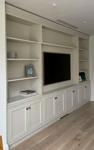 Built-in white wooden entertainment unit with cabinets and shelves