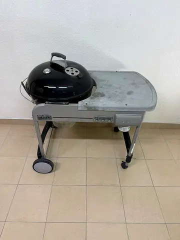 The Weber Performer charcoal grill features a side table for preparation.