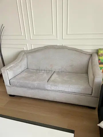 Light grey 2-seater upholstered sofa with nailhead trim from HomeCenter