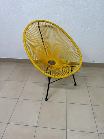 The Acapulco chair in yellow features a classic mesh design and a black metal frame.