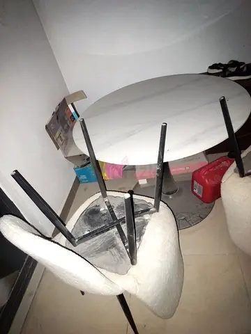 Small round marble-effect dining table with two cream upholstered chairs