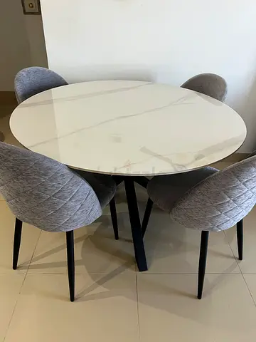 Round white marble-effect dining table with 4 grey upholstered chairs