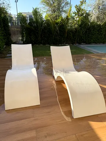 Pair of modern white outdoor lounge chairs - curved design for swimming pool
