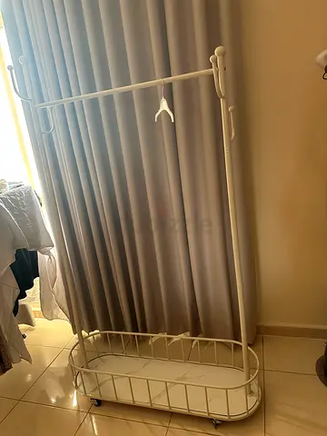 White metal clothes rack with bottom shelf and wheels