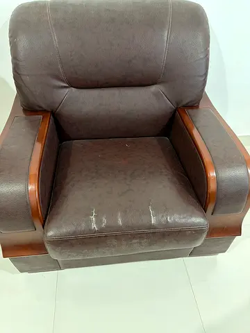 Brown leather-look cushioned armchair with wooden frame - used