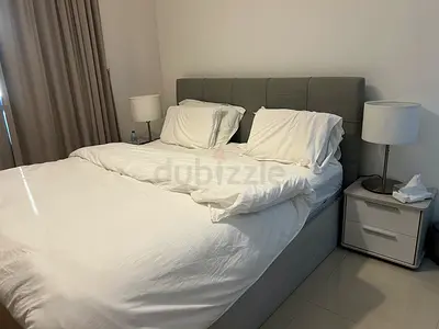 Grey upholstered double bed frame with mattress and bedside tables