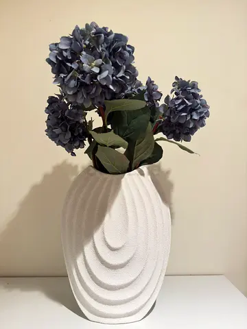 Decorative white textured vase with artificial hydrangea arrangement
