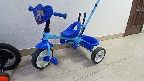 Blue toddler tricycle with push handle and storage basket - good used condition