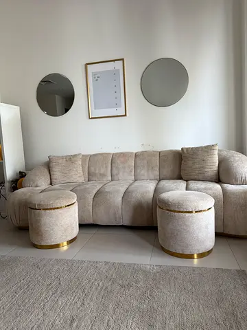 Light beige curved fabric sofa with 2 matching round ottomans
