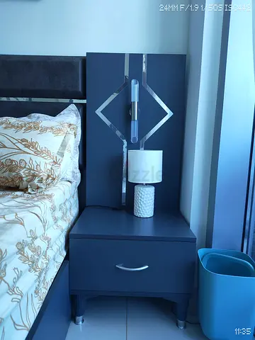 Dark grey bedside nightstand with drawer and decorative headboard panel