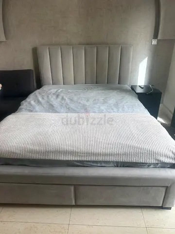 Light grey upholstered double bed with padded headboard and two drawers for storage - good condition