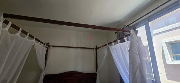 Wooden Four-Poster Bed with Canopy and Sheer Curtains