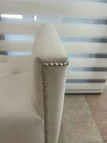 Light beige upholstered armchair with nailhead trim