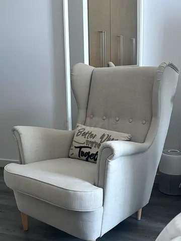 Light grey upholstered armchair with button back and wooden legs