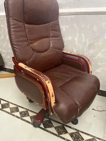 Used brown leather armchair with wooden arms