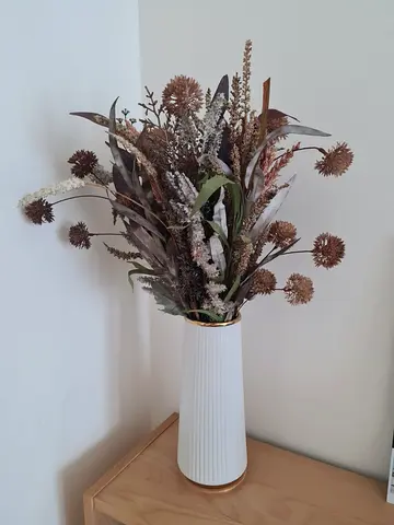 Tall white ceramic vase with dried floral arrangement.