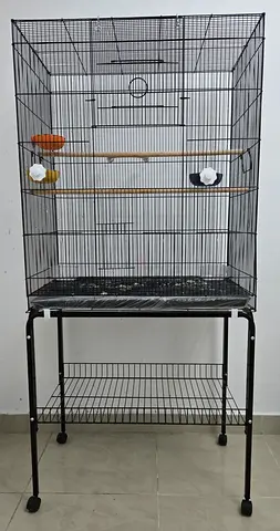 Large metal bird cage on stand with perches, food and feeding bowls.