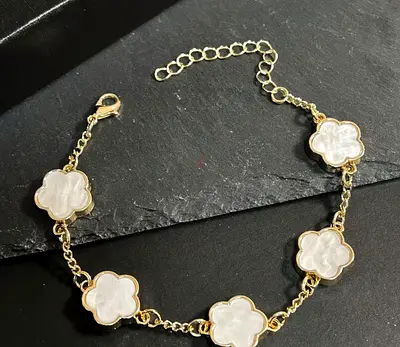 Gold-tone bracelet with white mother-of-pearl clover charms, adjustable