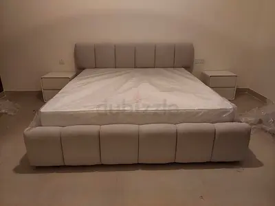 Light grey upholstered double bed with mattress and two bedside tables