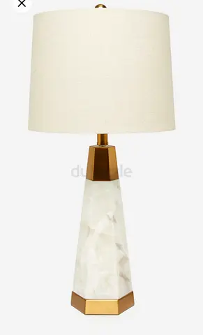 This is a contemporary table lamp featuring a white alabaster marble tapered base with gold-finished