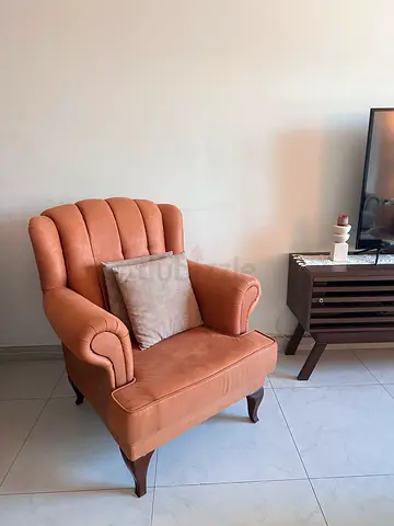 Comfortable tan leather upholstered armchair with wooden legs