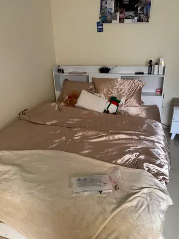 Queen bed with white headboard with secret storage on the headboard