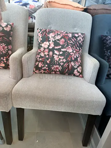 Pair of light grey upholstered armchairs with floral cushions