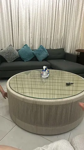 Round woven rattan-style coffee table with glass top