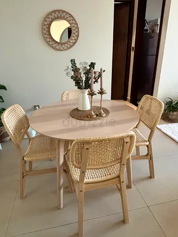 Round wooden dining table with 4 woven cane chairs.