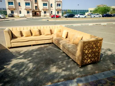 Large L-shaped beige velvet corner sofa with decorative wooden ends