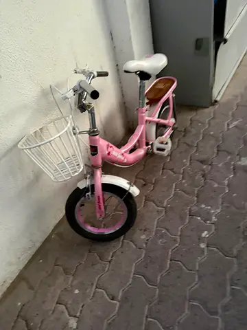 Pink kids bicycle with training wheels and basket