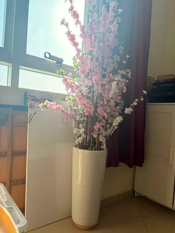 Tall white floor vase with artificial pink blossom branches