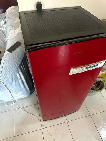 Compact red mini fridge in good working condition .