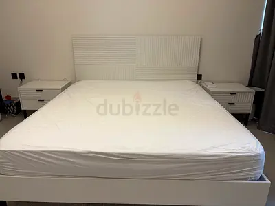 One white double bed, two bedside tables, and a dressing table