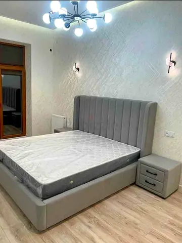 Grey upholstered double bed with mattress and matching bedside table