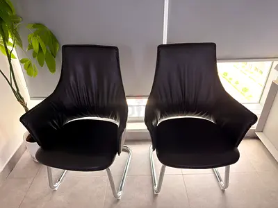 Pair of modern black leather guest chairs with chrome sled legs