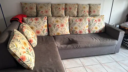 Large L-shaped grey fabric sofa with floral cushions - good condition