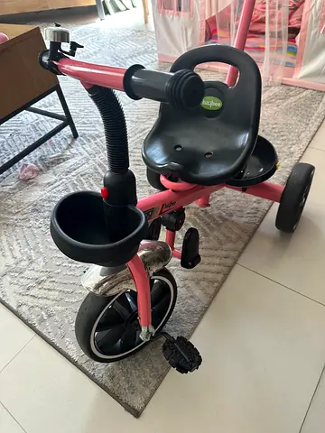 Pink toddler tricycle with push handle and storage bucket