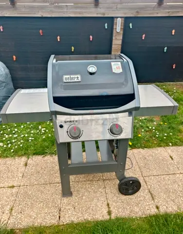 Weber Spirit II E-210 gas grill featuring a black porcelain-enameled lid and silver side tables