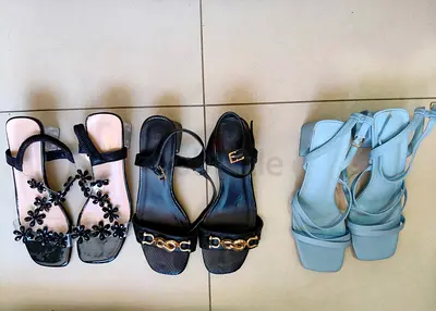 Four pairs of women’s sandals — black floral, shiny, chain-detail and light blue block-heel